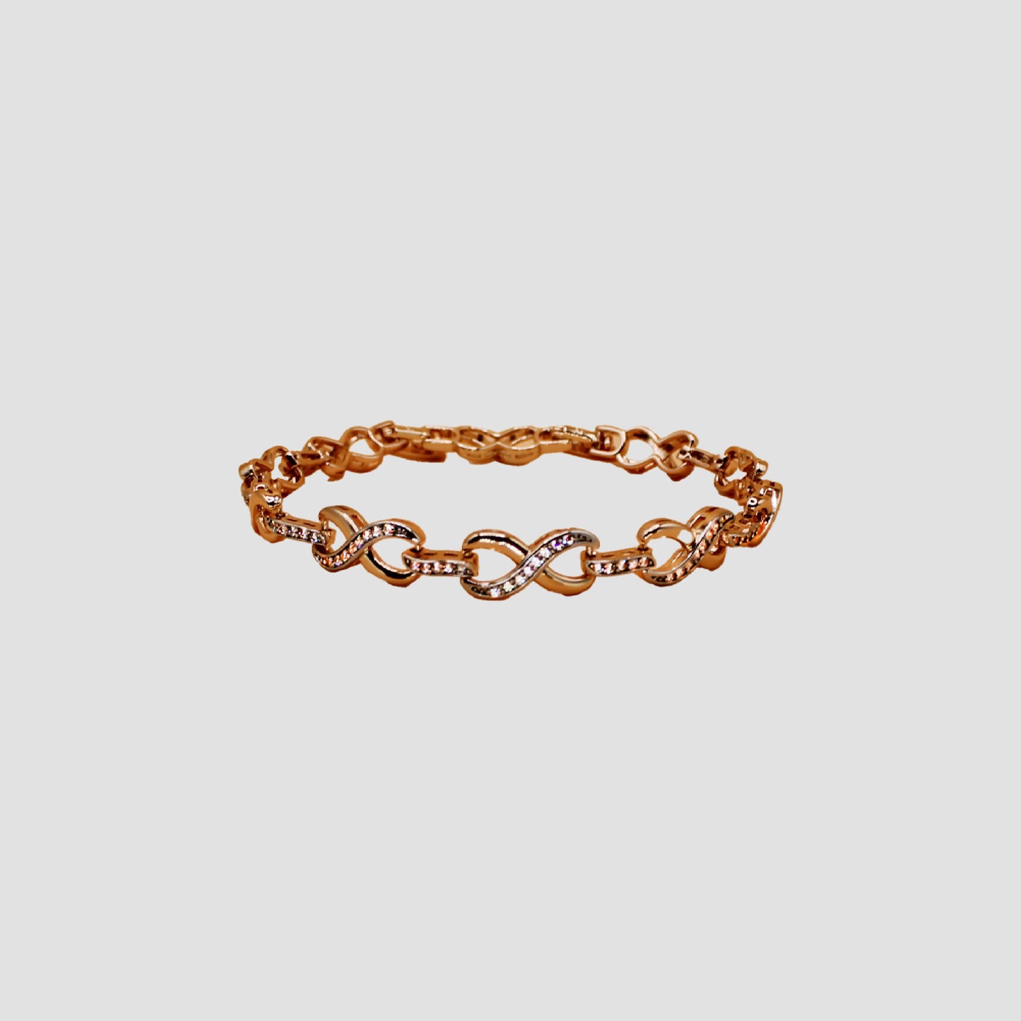 Gold-colored bracelet with intertwined infinity-shaped links, adorned with simulant diamonds.