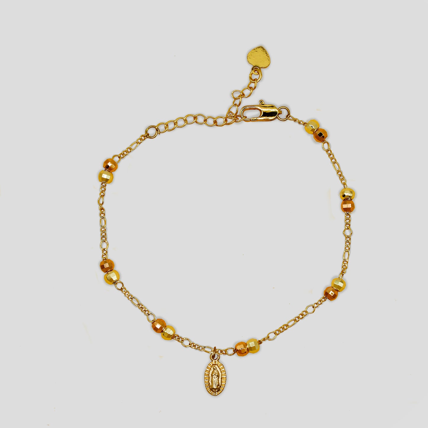 Delicate gold-colored bracelet with small round beads, an adjustable clasp with a heart charm, and a Virgin Mary pendant.
