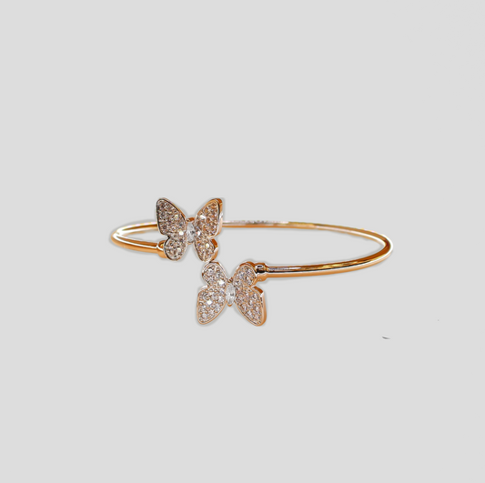 Gold-colored bracelet with two butterfly-shaped designs adorned with simulant diamonds.