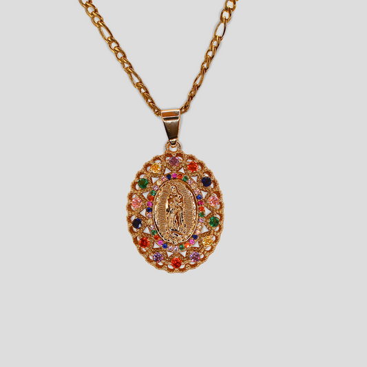 A gold-tone necklace with an oval pendant featuring a religious figure, surrounded by colorful gemstones on a lattice design, hanging from a gold chain.