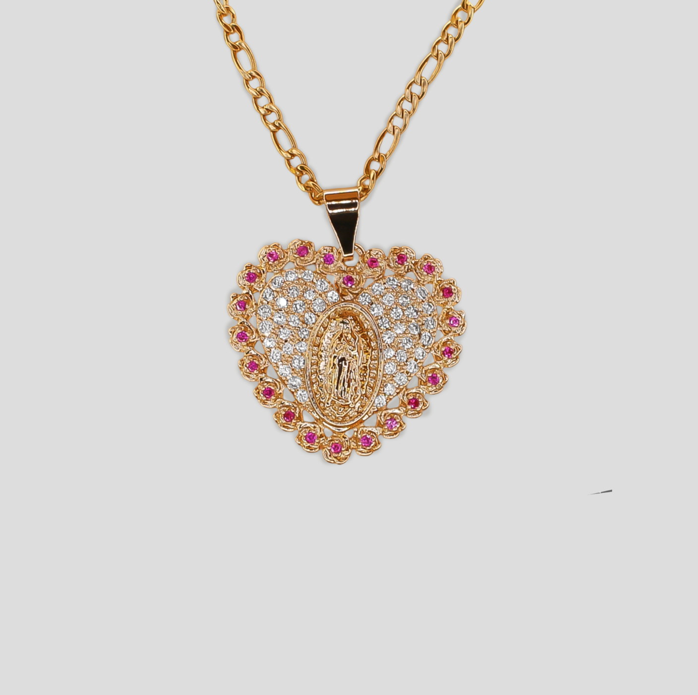 Gold-colored heart-shaped pendant necklace featuring a detailed Virgin Mary in the center, surrounded by simulant diamonds and pink gemstones.