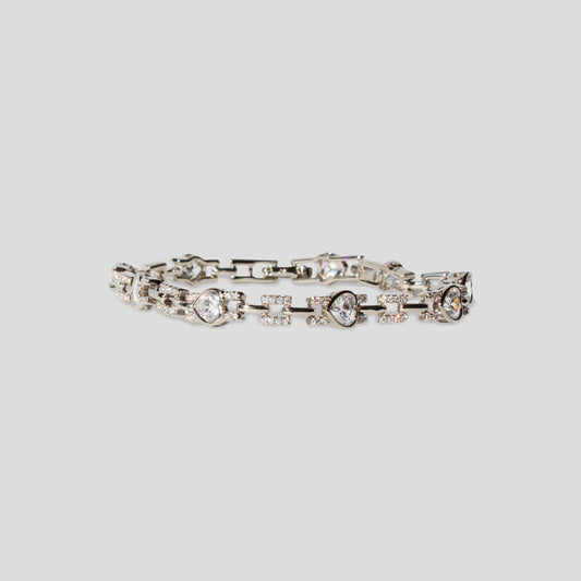 Silver-colored bracelet with heart-shaped simulant diamonds set in a chain link design.