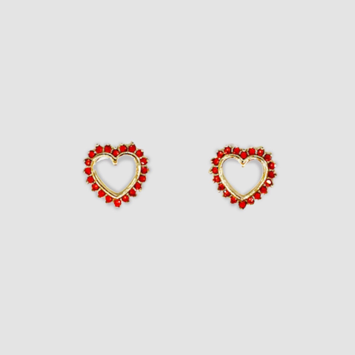 Gold-colored heart-shaped stud earrings adorned with red gemstones around the open-heart design.