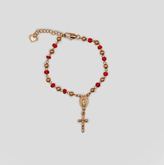 Gold-colored bracelet with red beads, featuring a religious medallion of the Virgin Mary and a hanging cross charm.