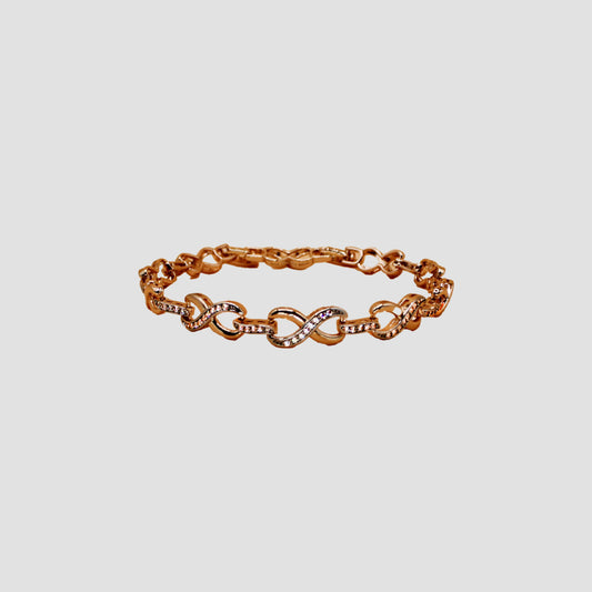 Gold-colored bracelet with intertwined infinity-shaped links, adorned with simulant diamonds.