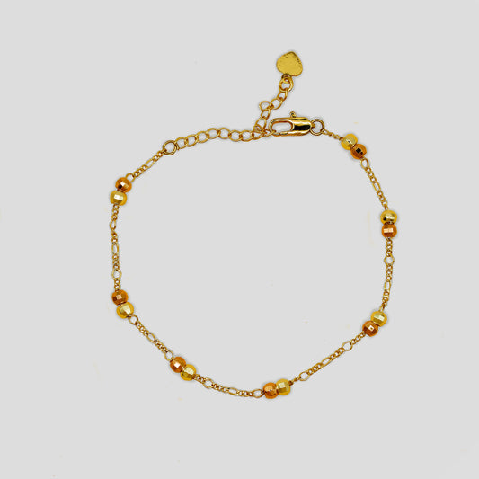 Delicate gold-colored bracelet with small round beads and an adjustable clasp with a heart charm.