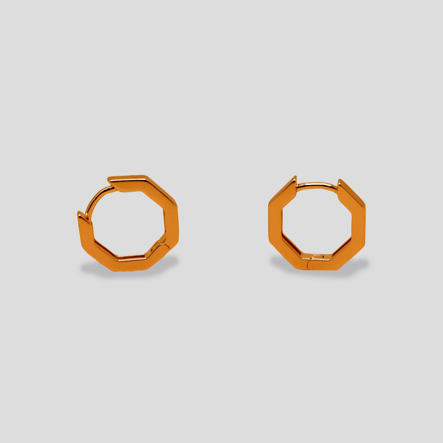 Pair of gold-colored hexagonal hoop earrings, showcasing a minimalist and geometric design with a smooth finish.