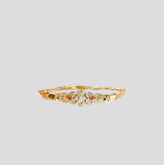 A gold-colored bracelet with an intricate design featuring heart-shaped elements and small red and green gemstones. The bracelet has a central decorative piece that includes a detailed motif of St. Benedict with additional sparkling stones embedded around it.