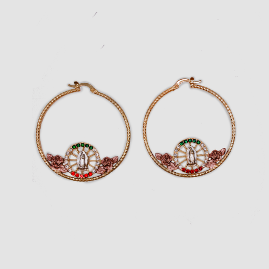 A pair of large gold color hoops with a small circle in the center surrounded by green, white, and red gemstones with the Virgin Mary in the center; with pink roses on both sides of the circle.