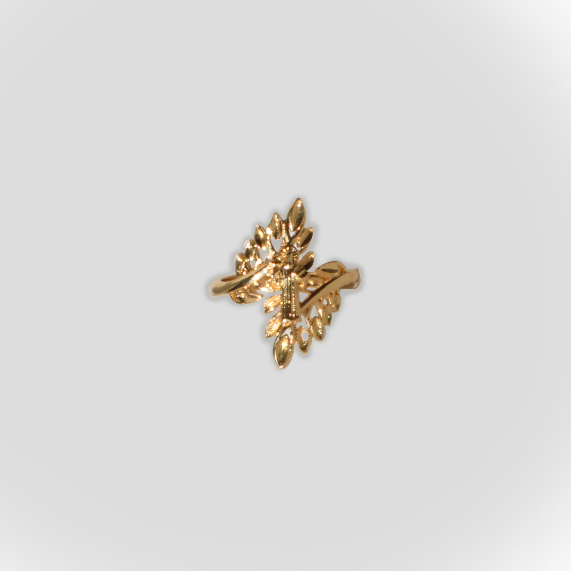 The image features a gold-toned ring with a Saint Benedict and a olive branch botanical design.