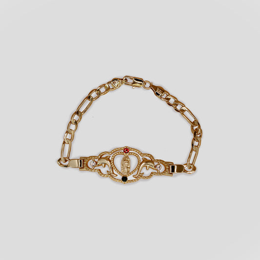 A gold-toned bracelet featuring a central decorative element with the San Judas, encircled by intricate designs, flanked by gemstones, and dolphin figures