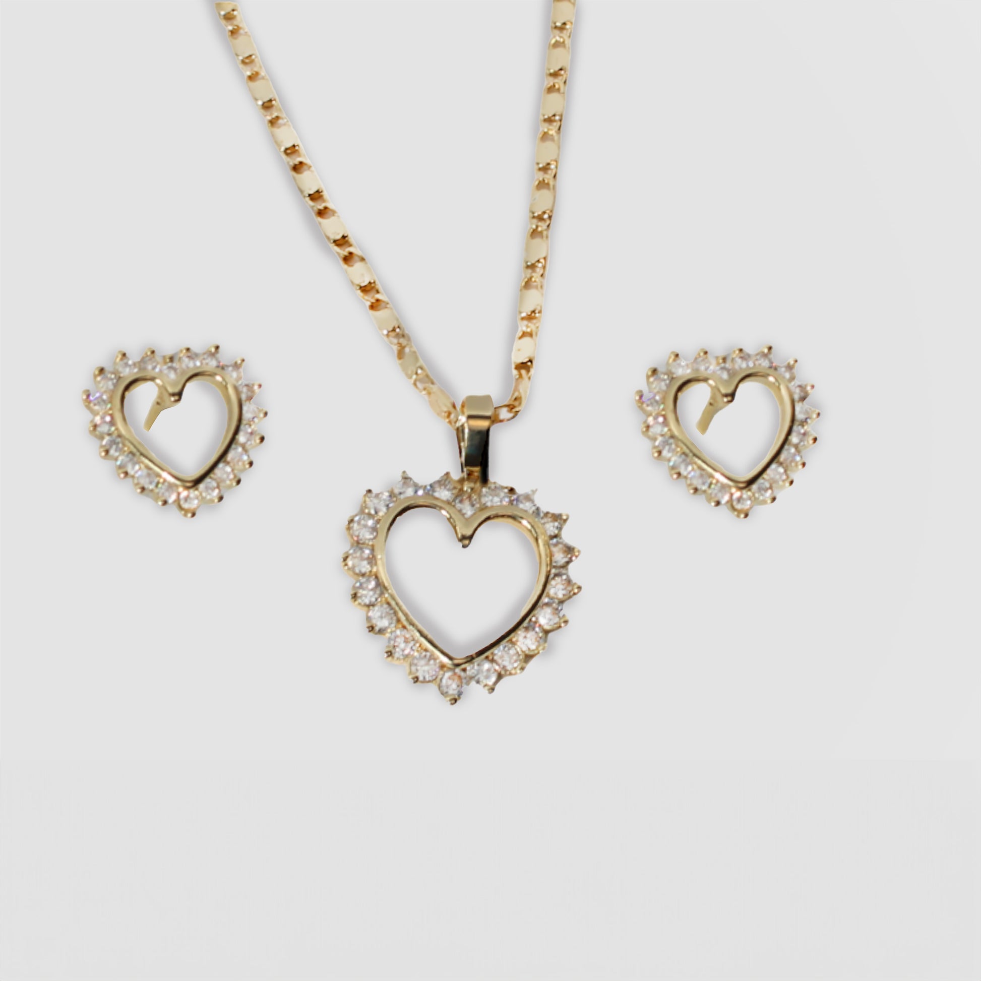 Gold-colored heart-shaped necklace and earrings set, featuring red gemstones around the open-heart design.